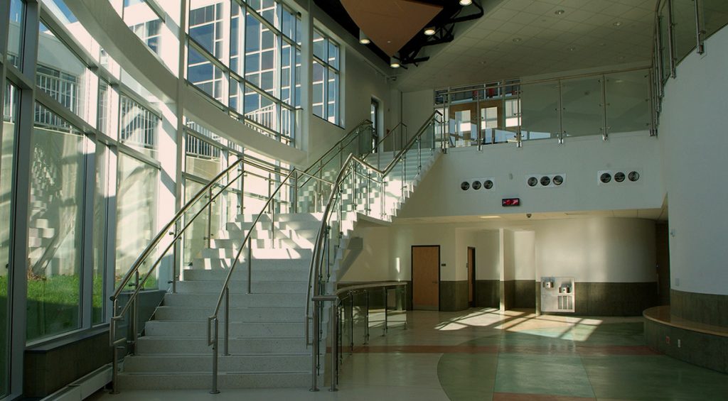 Open atrium with stairs on the left. Windows beside the staircase let light into the atrium