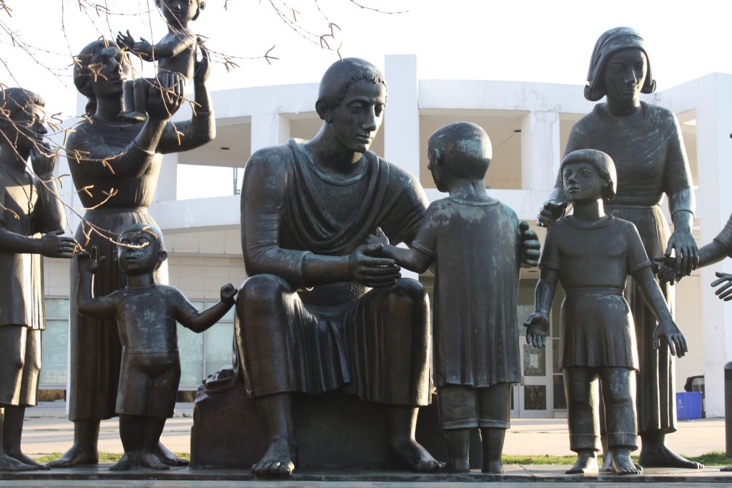 Statues outside the school. A man and a woman are tending to small children